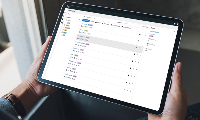 Personne tenant une tablette affichant une application de gestion des tâches avec une liste de tâches et leurs statuts.