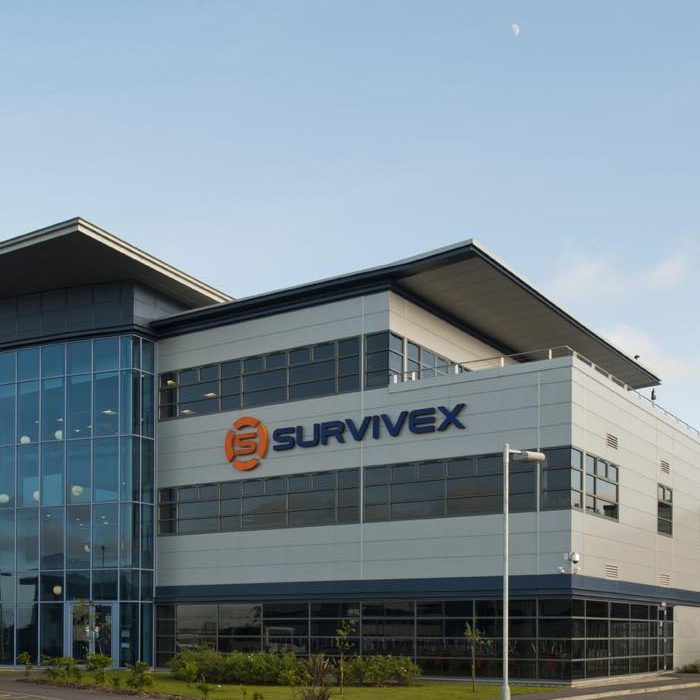 Modern office building with "Survivex" logo on it, featuring large glass windows and a parking lot with a few cars in front.
